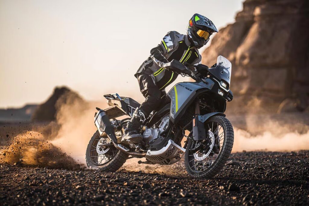 Rider on an adventure bike kicking up dust on rocky desert ground