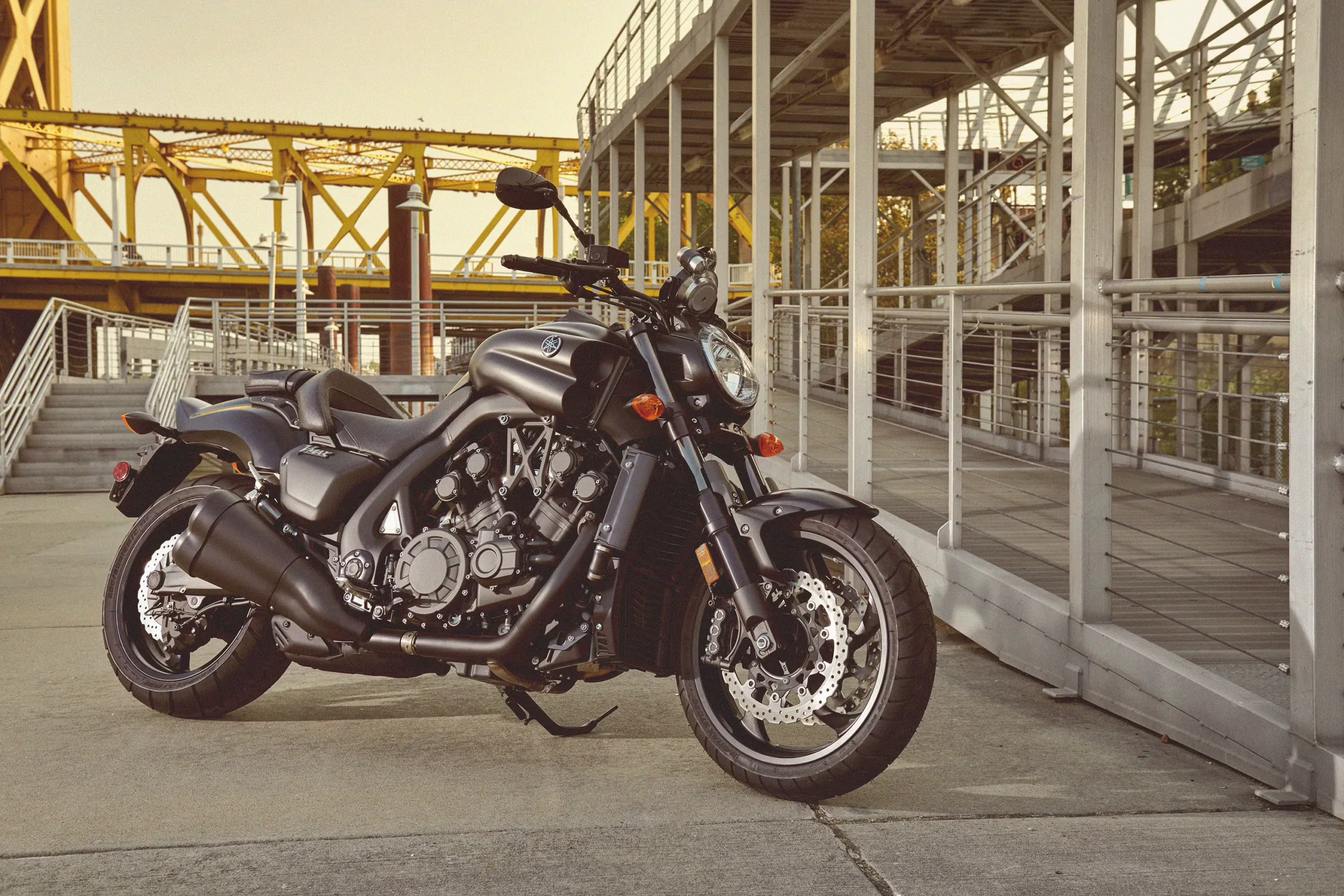 Black Yamaha V-Max parked in front of a yellow steel bridge
