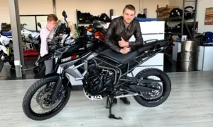 Rider leaning on a black Triumph Tiger 800 XCx in a showroom