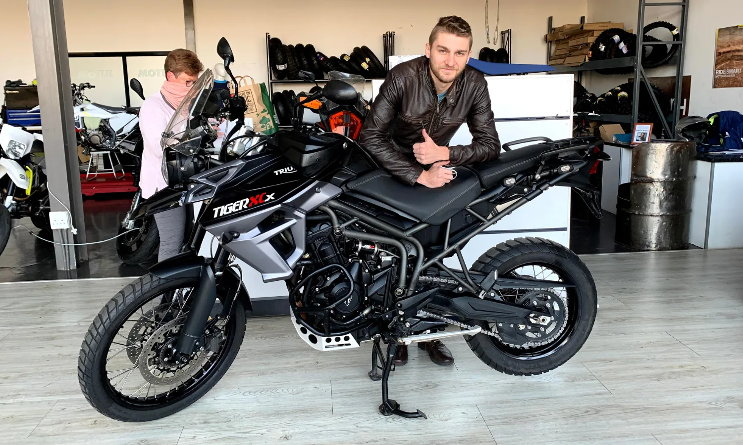 Rider leaning on a black Triumph Tiger 800 XCx in a showroom