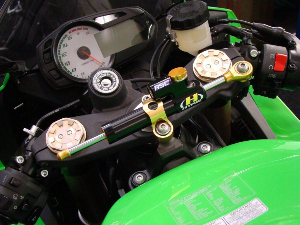 Hyperpro steering damper mounted across the top yoke of a green sports motorcycle