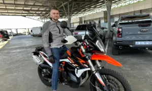 Rider sitting on an orange KTM 790 Adventure R under a carport