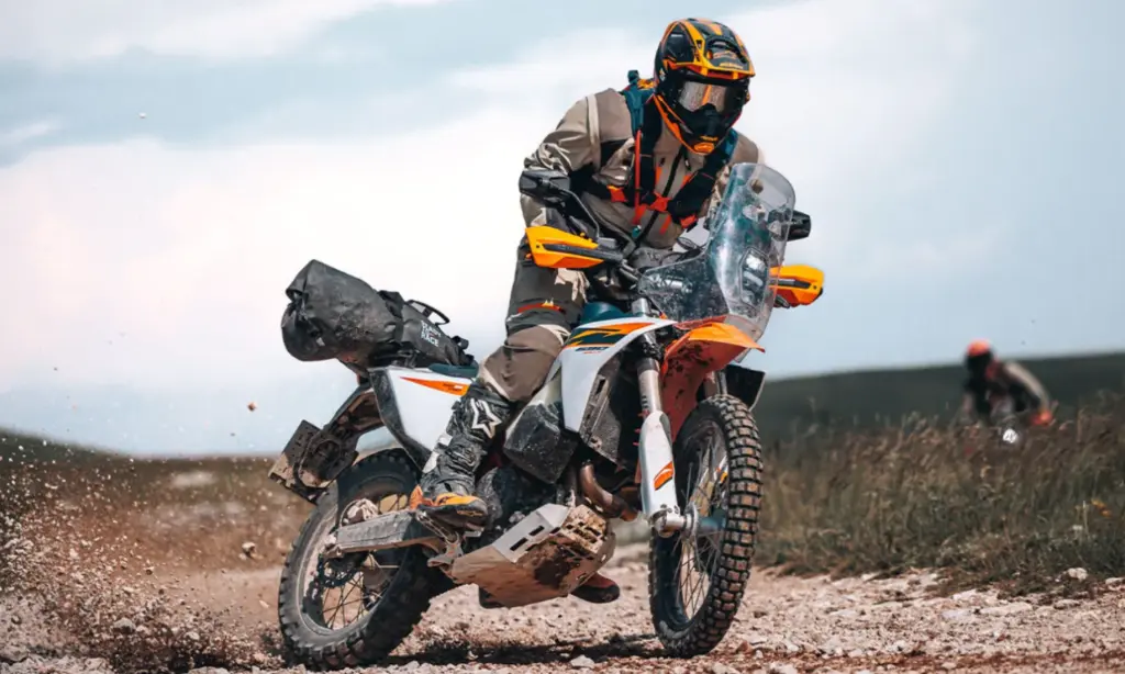 Rider standing on the pegs of a loaded 2027 KTM 690 Rally on a gravel track