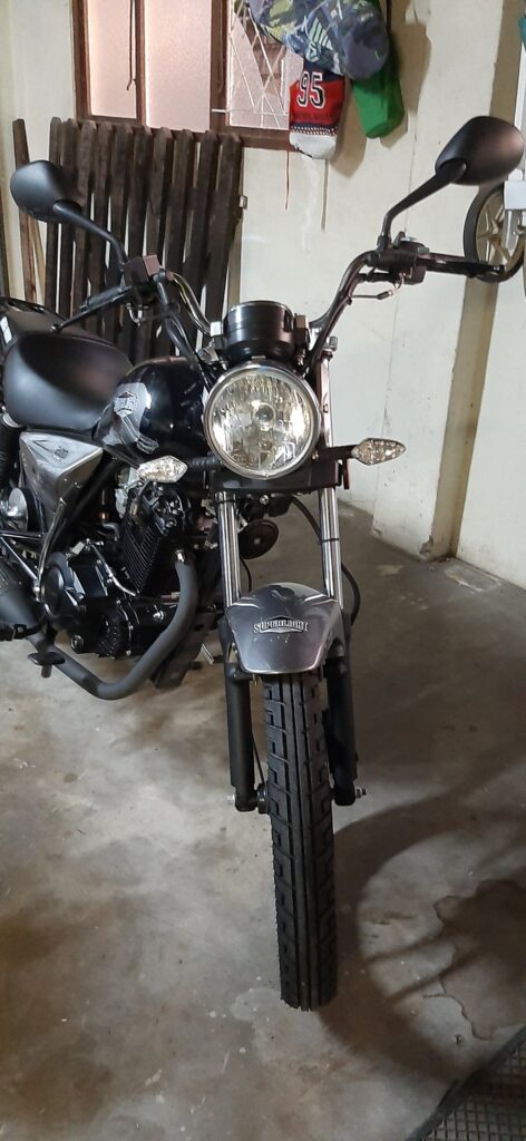 Front view of a black learner motorcycle parked in a garage