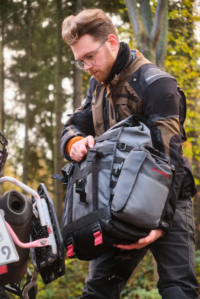 Rider fitting a Turkana Gear HippoHips soft saddlebag to a Triumph