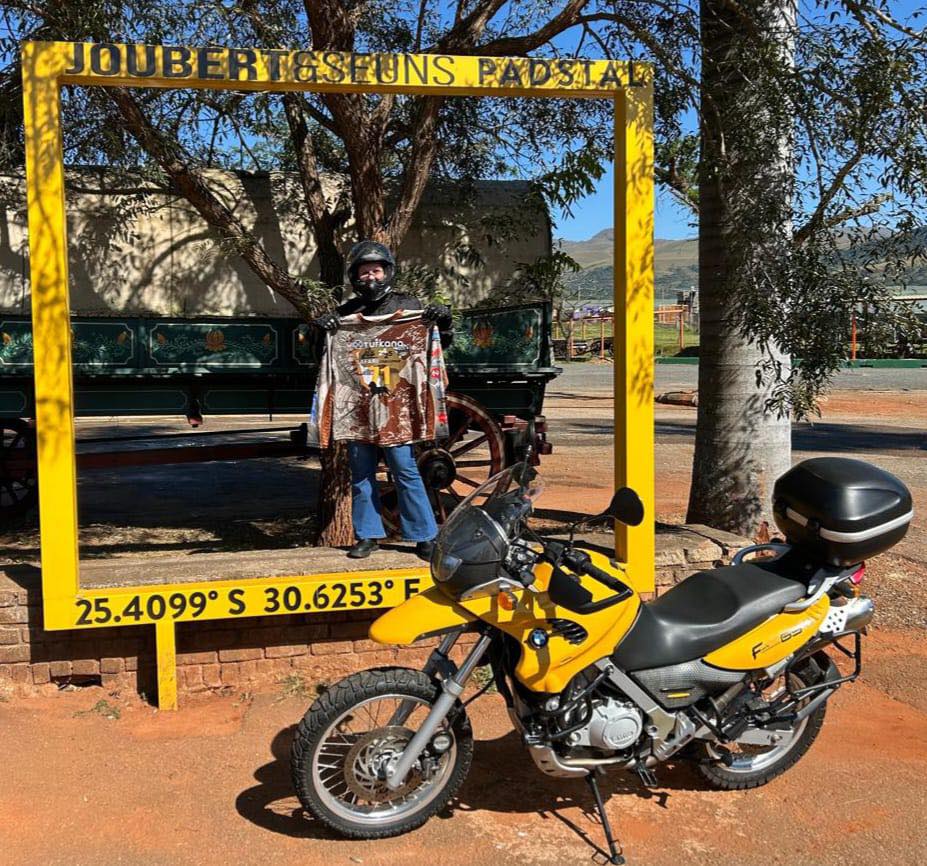 Rider in a yellow photo frame beside a yellow BMW F 650 GS on the Turkana Safari Challenge