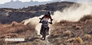 Rider on a Triumph adventure bike kicking up dust on a hillside trail