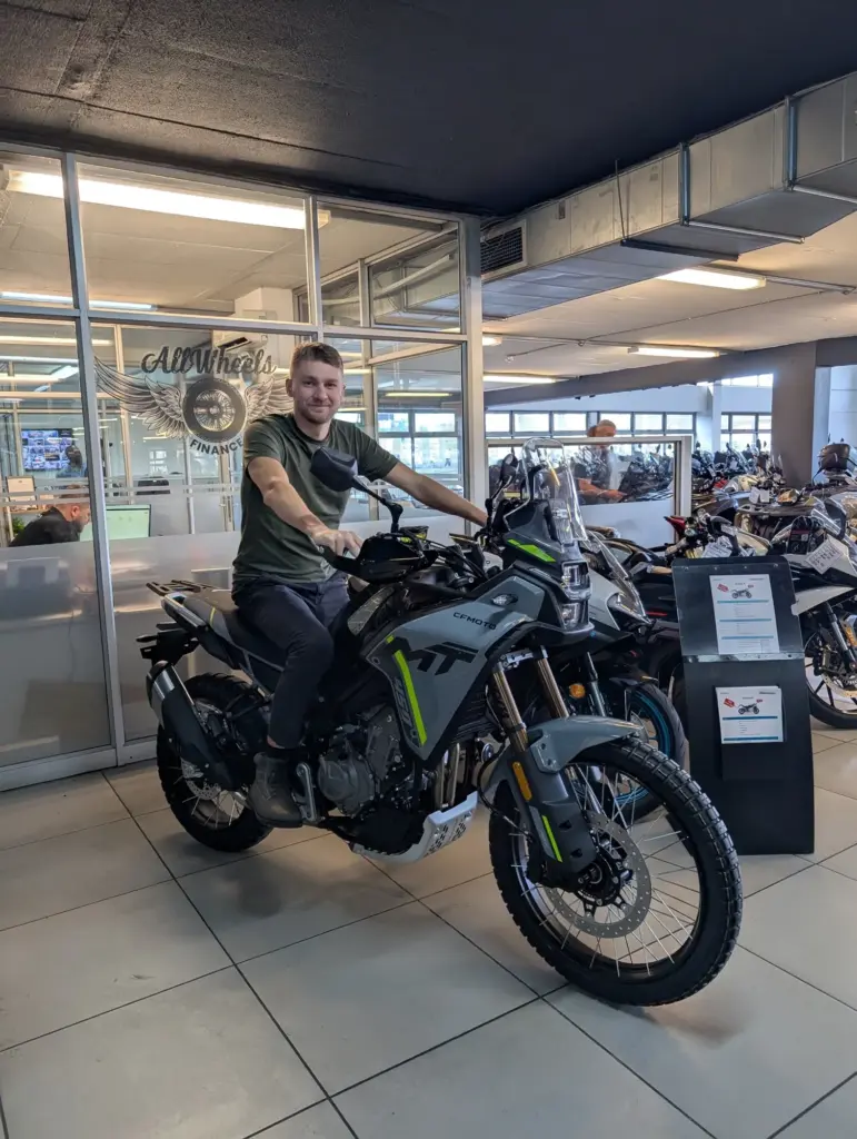 Rider seated on a CFMOTO 800MT-X inside a motorcycle dealership