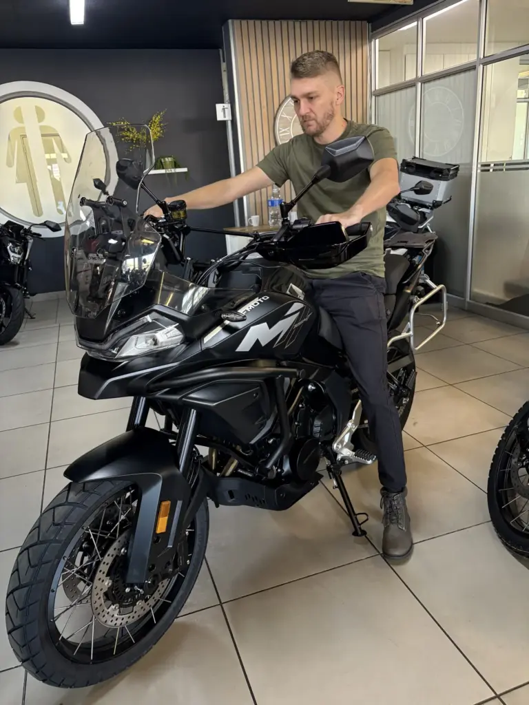 Rider sitting on a black CFMOTO 700MT in a showroom