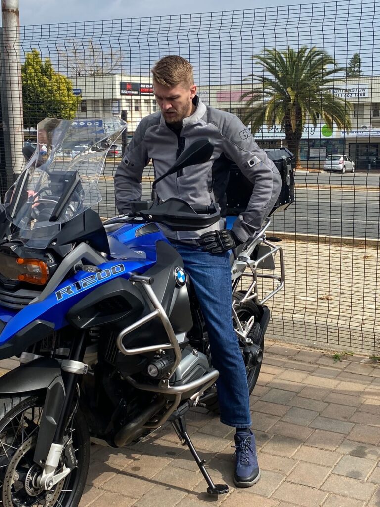 Rider standing beside a blue BMW R 1200 GS Adventure