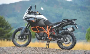 KTM 1190 Adventure R parked on gravel in front of green hills