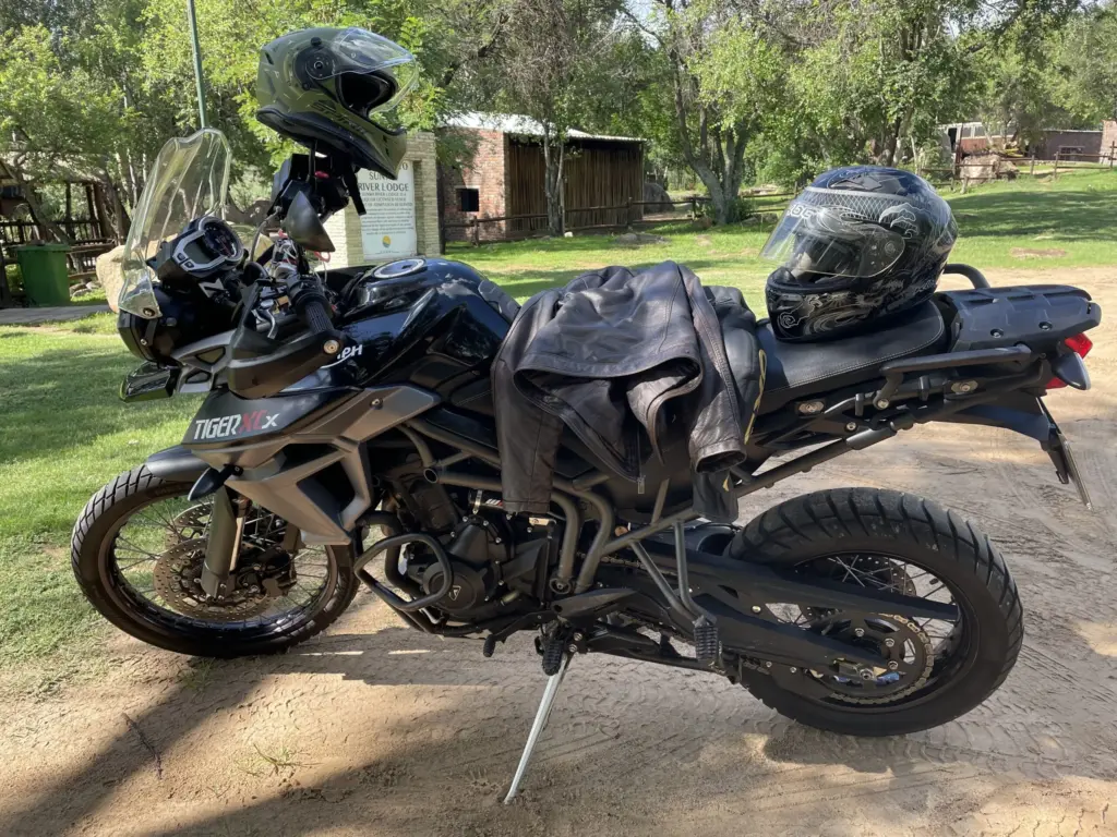 Triumph Tiger 800 XCx with helmets and a jacket, parked on dirt