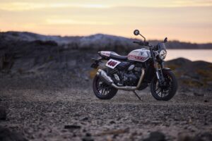 Triumph Tracker 400 in Aluminium Silver with red race graphics, parked on gravel at dusk